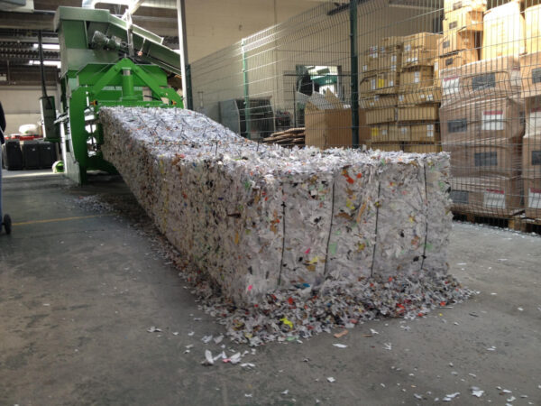 A horizontal baler with a bale of waste exiting the baler